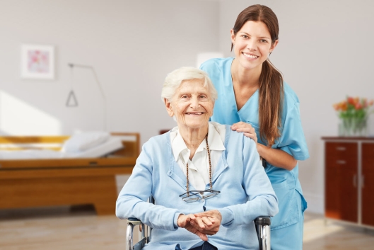 Eine Pflegefachkraft und eine Seniorin schauen in die Kamera