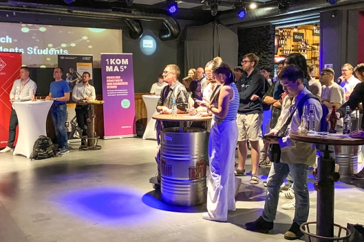 Blick in den Raum der Tech-Veranstaltung Pitch Your Tech, Aussteller stehen an Ihren Ständen